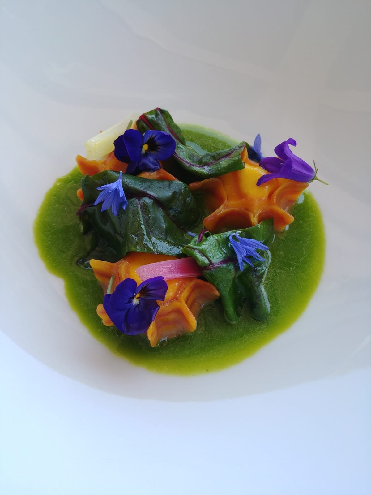 Ravioli piastrati di patate ripieni di crema di melanzane, decorati con fiori di rosmarino