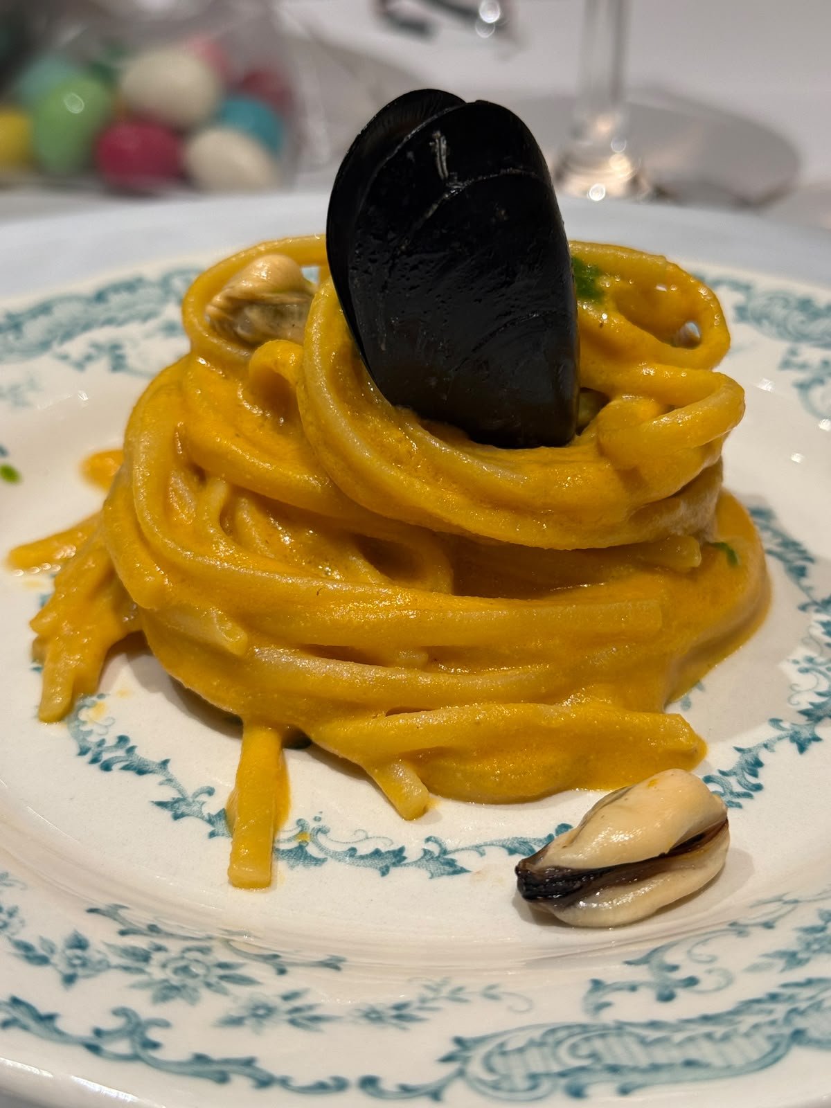 Spaghetti a nido in crema gialla con cozze, guarniti con un guscio di cozza